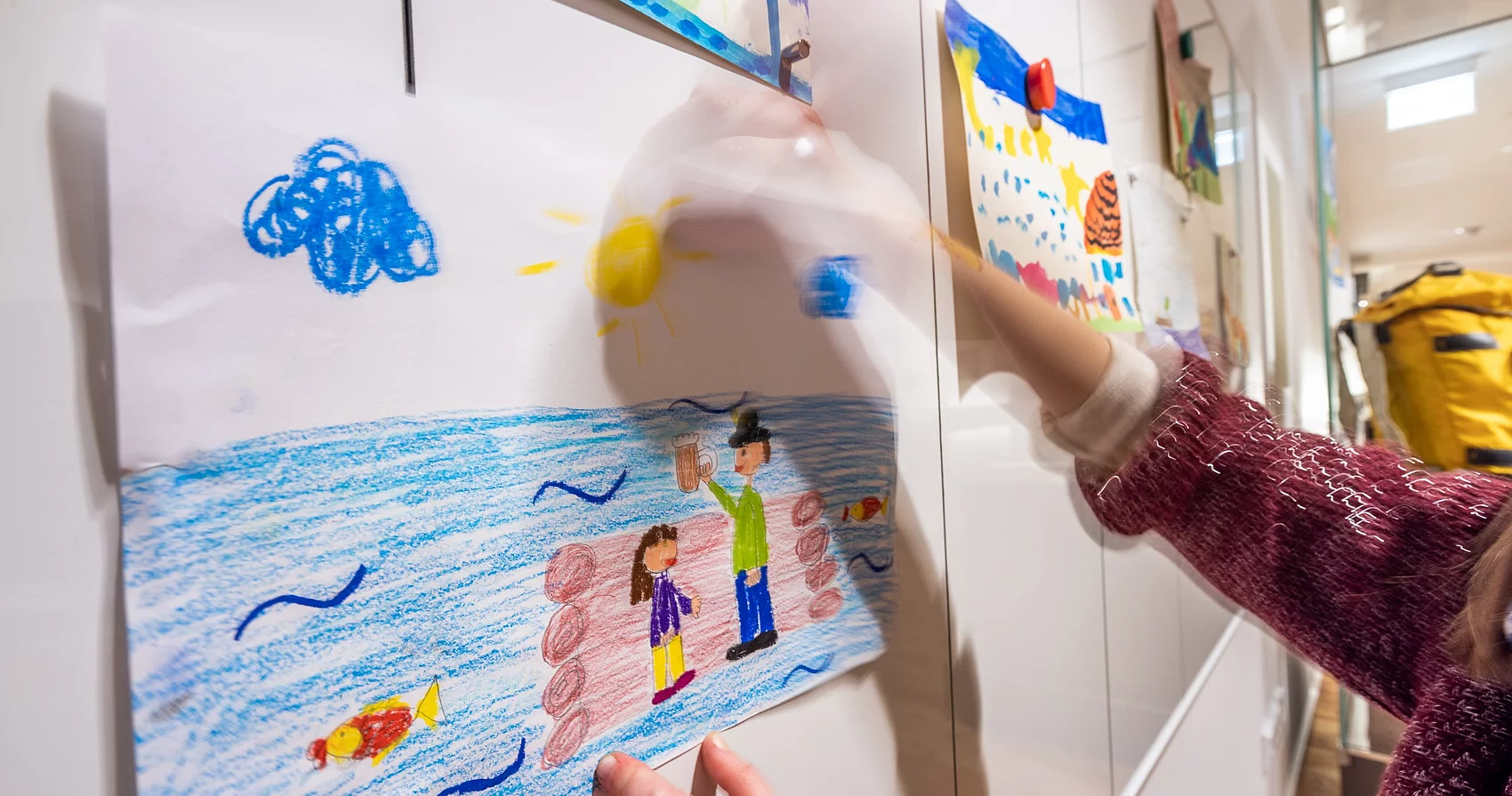Kind pinnt ein Bild an die Wand